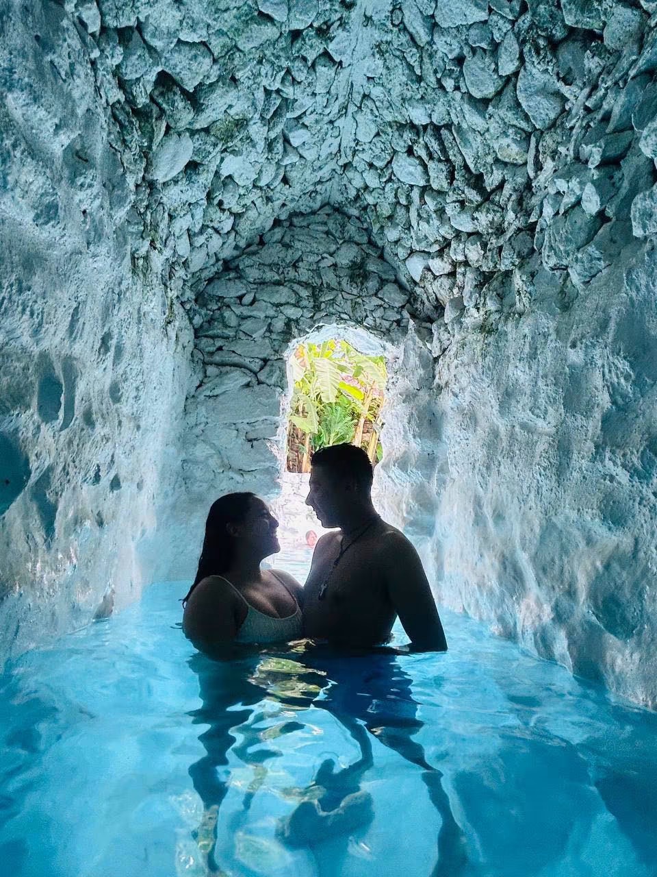 Pareja disfrutando una gruta de agua azul